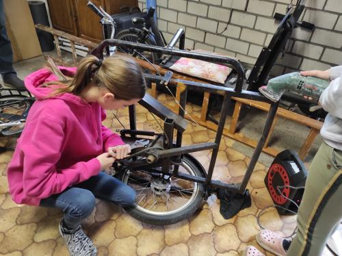 Britt bezig om de oude bakfiets uit elkaar te halen.